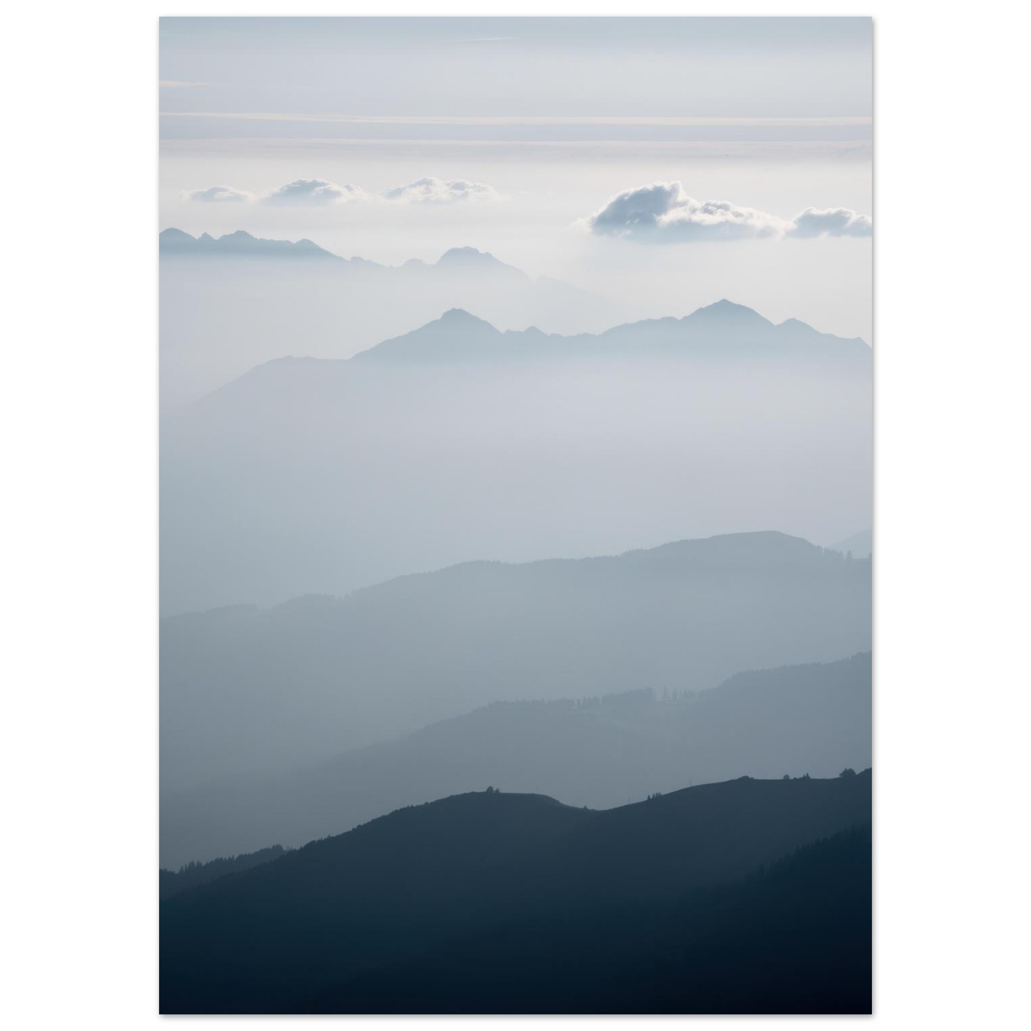 Layered mountain ranges in atmospheric perspective, with forested foreground darkening to misty peaks and clouds in the distance.